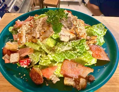 a green salad on a blue plate on a table at Pupa Women Hostel in Patong Beach