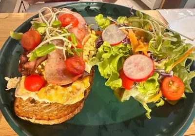 a plate of food with a sandwich and a salad at Pupa Women Hostel in Patong Beach
