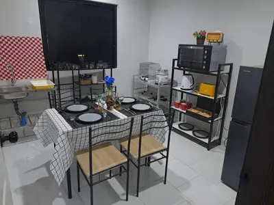 a kitchen with a table with chairs and a tv at 2 bedroom house in Thalang in Ban Pak Lak