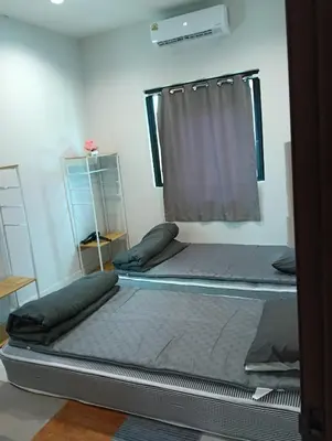 two beds in a room with a window at 2 bedroom house in Thalang in Ban Pak Lak