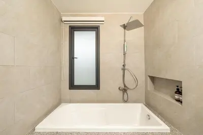 a white bath tub in a bathroom with a mirror at The Pinnacle Katanoi in Kata Beach