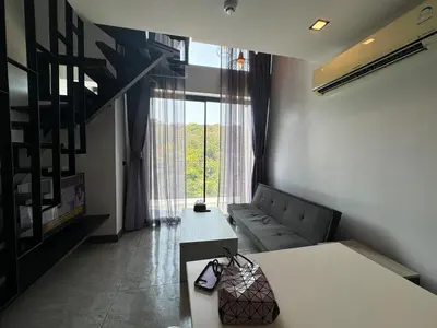 a living room with a couch and a large window at Utopia Loft Condo in Nai Harn Beach