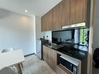 a kitchen with a black counter top and wooden cabinets at Utopia Loft Condo in Nai Harn Beach