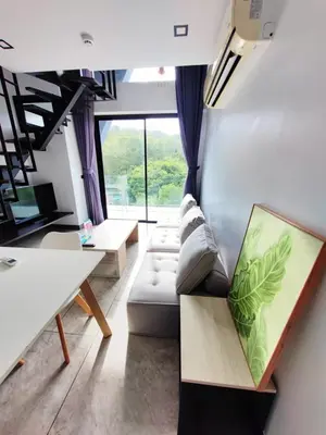 a living room with a couch and a large window at Utopia Loft Condo in Nai Harn Beach