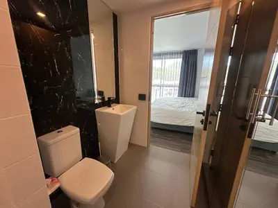 a bathroom with a toilet and a sink and a bed at 1-bedroom apartment Naiharn Beach B403 in Rawai Beach