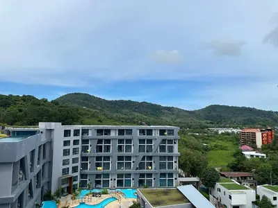 a view of a building with mountains in the background at 1-bedroom apartment Naiharn Beach B403 in Rawai Beach