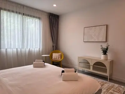a bedroom with a bed and a chair and a window at Luxury 3BR Triplex Jacuzzi & Sea View PANDORA RESIDENCES in Nai Harn Beach