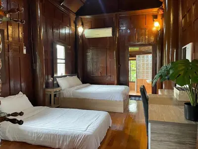 a bedroom with two beds and a table with a plant at Niyang Siam House in Nai Yang Beach