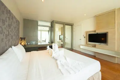 a bedroom with a large white bed with a flat screen tv at Yenna Apartment in Kamala Beach