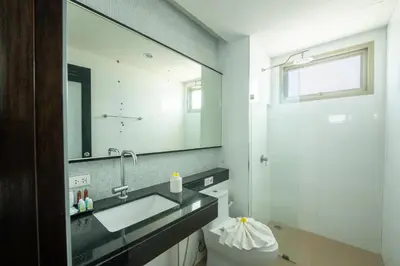 a bathroom with a sink and a mirror and a toilet at Yenna Apartment in Kamala Beach
