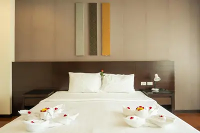a bed with white sheets and flowers on it at Yenna Apartment in Kamala Beach