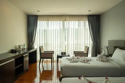 a hotel room with two beds and a table and chairs at Yenna Apartment in Kamala Beach