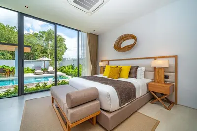 a bedroom with a large bed and a chair at Botanica Foresta - 4 Bedroom Spacious Luxury Pool Villa in Layan in Ban Phru Champa