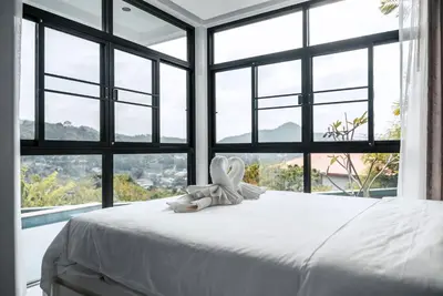 a white bed with a bow on it in a room with windows at Namara The Residences A in Kamala Beach