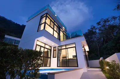 a white house with large windows at night at Namara The Residences A in Kamala Beach