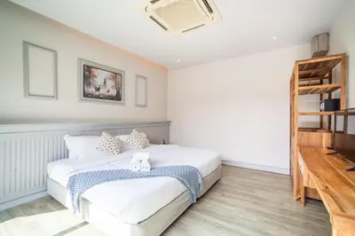 a bedroom with a white bed and a wooden shelf at Tropical 4 Bedroom Pool Villa in Laguna Phuket