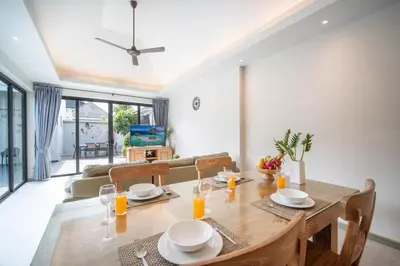 a dining room and living room with a table and chairs at Tropical 4 Bedroom Pool Villa in Laguna Phuket