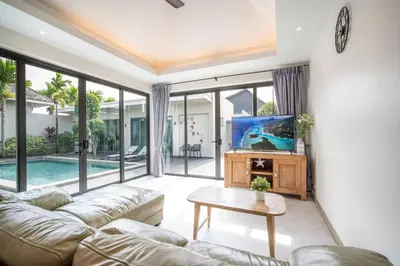 a living room with a couch and a tv at Tropical 4 Bedroom Pool Villa in Laguna Phuket