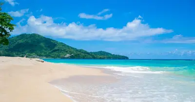 a sandy beach with a mountain in the background at TJ Patong HOSTEL in Patong Beach