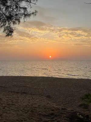 a sunset on the beach with the sun in the distance at TENT Maikhao in Ban Mai Salae