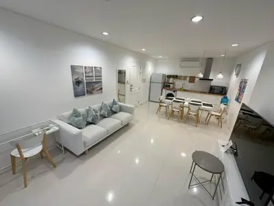 a white living room with a couch and a kitchen at Excellent apartment on Kamala in Kamala Beach