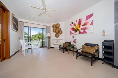 a living room with a ceiling fan and a table and chairs at Allamanda Premium Apartments Laguna Phuket in Laguna Phuket