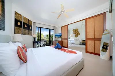 a bedroom with a white bed and a living room at Allamanda Premium Apartments Laguna Phuket in Laguna Phuket