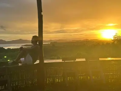 a person sitting on a bench watching the sunset at Phukhao thong in Ban Bang Chak