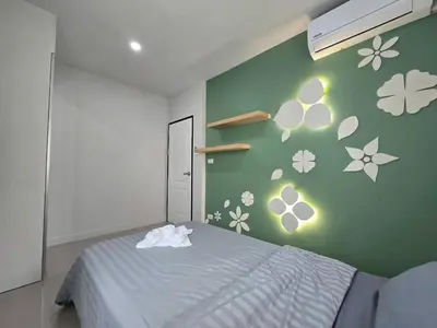 a bedroom with a bed and a green wall with flowers at MB Home in Ban Bang Khu
