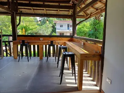 a large wooden bar with stools on a porch at Diindanghomestay in Ban Khao Klom