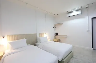 two beds in a room with white walls at Lfour phuket in Phuket Town