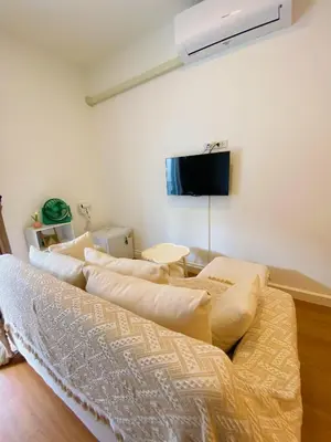 a room with a couch with pillows and a tv at SJ Beach House Patong in Patong Beach