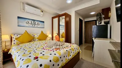 a bedroom with a large bed with yellow pillows at Уютная квартира рядом с пляжем Май Као in Ban Mai Salae