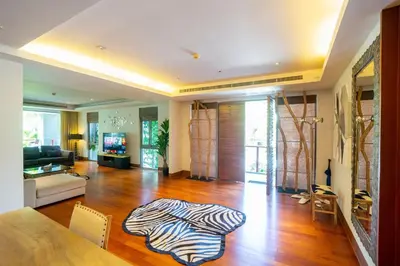 a living room with a wooden floor and a couch and a television at Suite of Naithon beachfront apartment in Nai Thon Beach