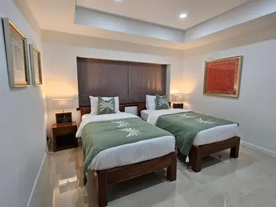 a bedroom with two beds with green comforters at Eden Villas Kamala in Kamala Beach
