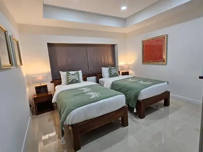 a bedroom with two beds with green and white sheets at Eden Villas Kamala in Kamala Beach