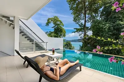 a woman laying on a chair next to a swimming pool at Private 3-Storey Pool Villa Atika 10, for 7, views of Patong Bay in Patong Beach