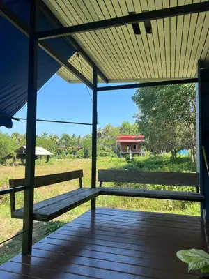 a bench sitting on a porch with a view of a field at Nature Home in Phang-nga