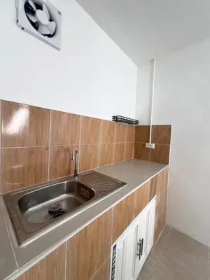 a kitchen with a stainless steel sink and wooden cabinets at Tim House Thalang Phuket 1 in Thalang