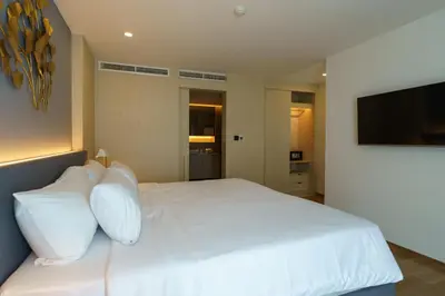 a white bed with white pillows and a flat screen tv at Amazing View Duplex La Vita in Phuket Town