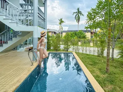 a woman in a bikini standing on the edge of a swimming pool at Casa Sakhu Beach Villa Phuket in Nai Yang Beach