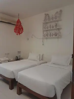 two beds in a room with white walls at Pimnara Boutique Hotel By Simply Serene in Patong Beach