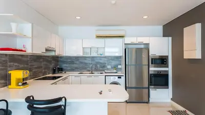 a kitchen with white cabinets and a stainless steel refrigerator at Apartment 2 bedrooms on Kamala in Phuket Town