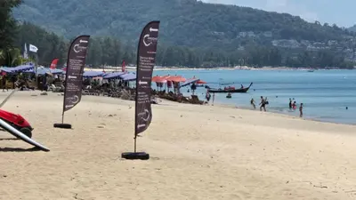 two flags on a beach with people in the water at Allamanda Laguna in Laguna Phuket