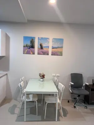 a table and chairs in a room with paintings on the wall at Chic Condo Karon A512 in Karon Beach