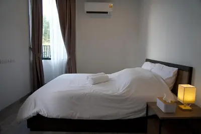 a bedroom with a white bed and a table with a lamp at Private pool villa bangtao - laguna park in Ban Phru Champa