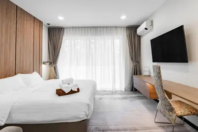 a hotel room with a bed and a tv at Med Village by Villacarte in Nai Harn Beach