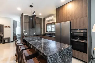 a kitchen with a black counter top and wooden cabinets at Med Village by Villacarte in Nai Harn Beach