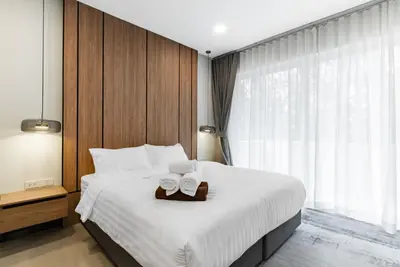 a bedroom with a bed with two towels on it at Med Village by Villacarte in Nai Harn Beach