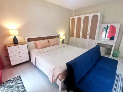 a bedroom with a large bed and a blue couch at Kata beach Townhouse BL2 in Kata Beach